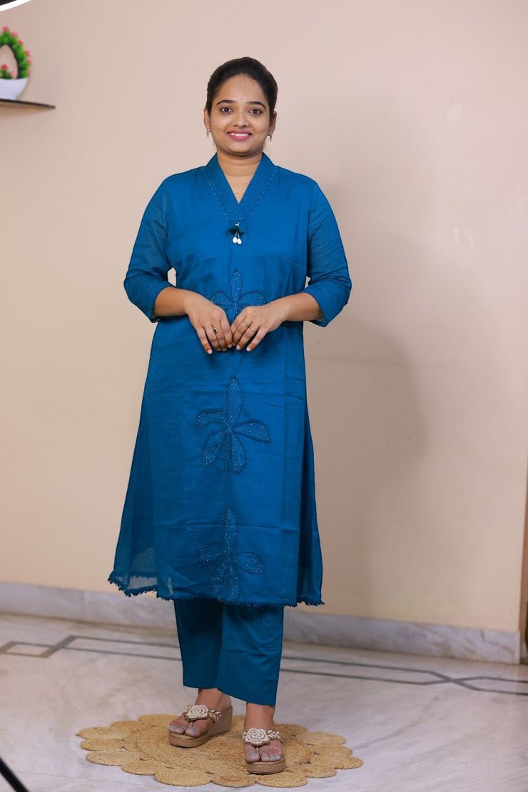 SreeVastra teal blue mul cotton three-piece dress with floral embroidery and V-neckline worn by a woman